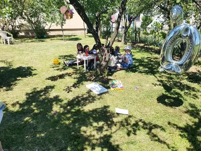 a group of children sitting around a table under a tree at Sobe i apartmani Djordjevic in Mladenovac