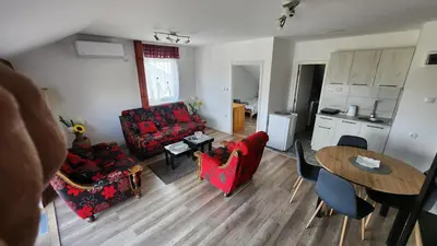 a living room with a red couch and a table at Sobe i apartmani Djordjevic in Mladenovac