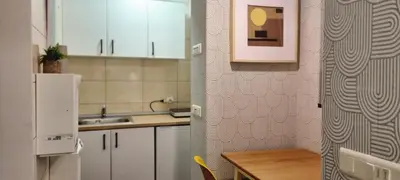 a kitchen with white cabinets and a table and a refrigerator at Mi Casita Studio in Belgrade