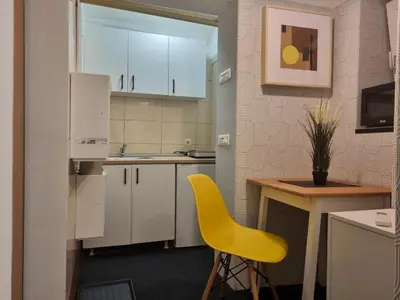 a kitchen with a yellow chair and a table at Mi Casita Studio in Belgrade