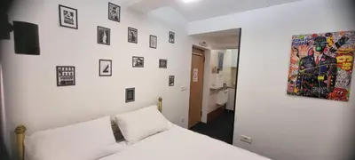 a bedroom with a white bed and pictures on the wall at Mi Casita Studio in Belgrade