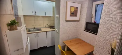 a kitchen with white cabinets and a table and a tv at Mi Casita Studio in Belgrade