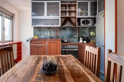 a kitchen with a wooden table in a room at Čubrina - central 2bdrm & 45m2 Rooftop Terrace in Belgrade