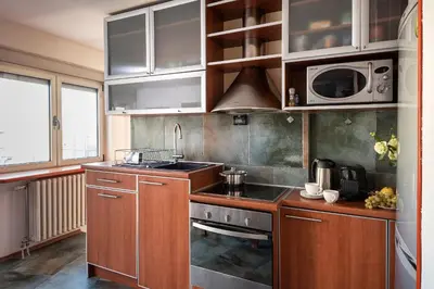 a kitchen with wooden cabinets and a sink and a microwave at Čubrina - central 2bdrm & 45m2 Rooftop Terrace in Belgrade