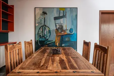 a wooden dining room table with chairs and a painting at Čubrina - central 2bdrm & 45m2 Rooftop Terrace in Belgrade