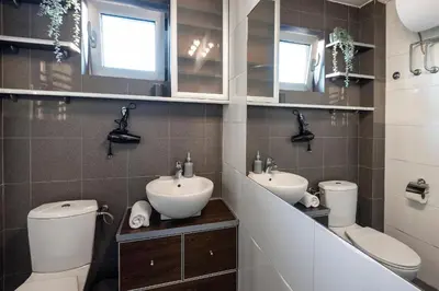 a bathroom with two sinks and a toilet and mirrors at Čubrina - central 2bdrm & 45m2 Rooftop Terrace in Belgrade