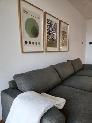 a couch in a living room with three pictures on the wall at Novi Dorcol Big in Belgrade