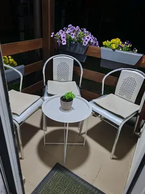 two chairs and a table on a balcony with flowers at Sveti Luka- OBRADOVIĆ SOKAK 41 in Šimanovci