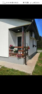 a small house with a balcony with flowers on it at Sveti Luka- OBRADOVIĆ SOKAK 41 in Šimanovci