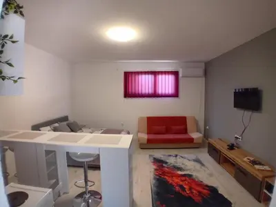 a living room with a couch and a red chair at AlejaPark in Železnicka Stanica Inđija Selo