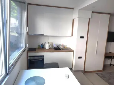 a small kitchen with white cabinets and a window at Asja studio in Belgrade