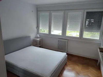 a bedroom with a bed and two windows at Tesla apartment - lovely 2 bedroom apartment in Belgrade