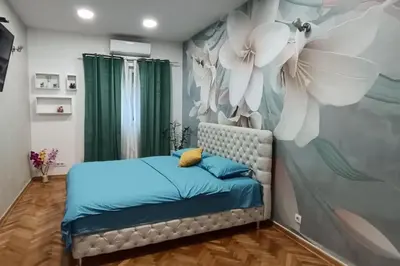 a bedroom with a bed with a flower mural at Venera Lux Apartman in Zemun