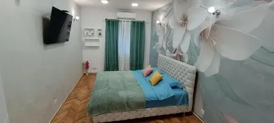 a bedroom with a bed and a wall with a flower mural at Venera Lux Apartman in Zemun