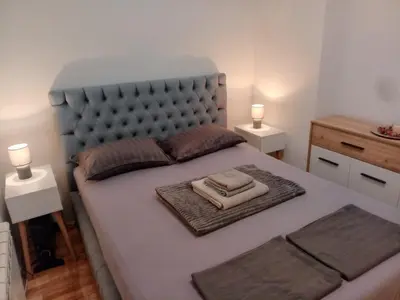 a bedroom with a bed with a blue headboard and two lamps at Apartman EXPO Surčin in Surčin