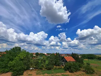 a house in a field under a cloudy sky at Apartman EXPO Surčin in Surčin