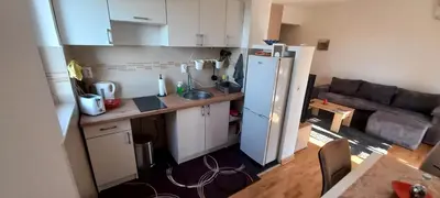 a small kitchen with a refrigerator and a couch at Apartman EXPO Surčin in Surčin