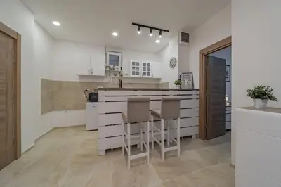 a kitchen with white cabinets and a bar with stools at Jordan Belgrade Apartment in Belgrade