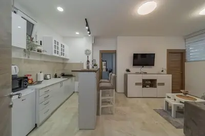 a large kitchen with white cabinets and a tv at Jordan Belgrade Apartment in Belgrade