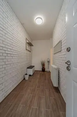 a hallway with a white brick wall and wooden floors at Jordan Belgrade Apartment in Belgrade