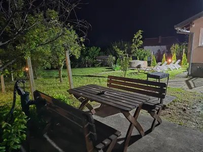 a picnic table and benches in a yard at night at Vila Nera in Železnička Stanica Karlovački Vinogradi