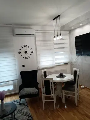 a dining room with a table and a clock on the wall at City011 studio PRIVATE GARAGE FREE in Belgrade