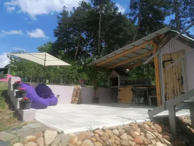 a backyard patio with a house and an umbrella at Apartman LAVANDA in Šumarak