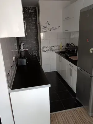 a kitchen with white cabinets and a black counter top at Apartman Maki in Belgrade