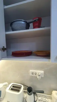 a kitchen counter with a stove with dishes on shelves at Smile 1 in Belgrade