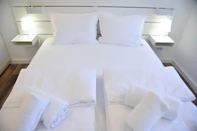 a white bed with white pillows and towels on it at Friendly Home ap Balkan-inn in Belgrade