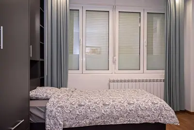 a bedroom with a bed and some windows at Anmador Stay in Belgrade