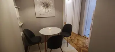 a dining room with a white table and black chairs at Maximus Apartments in Belgrade