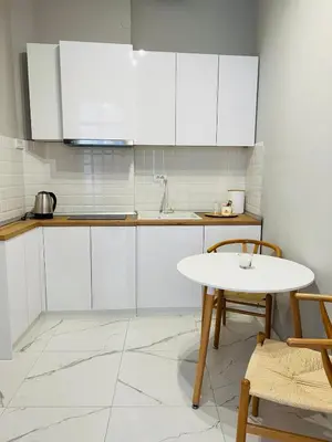 a kitchen with white cabinets and a white table at Maximus Apartments in Belgrade