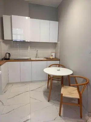 a kitchen with white cabinets and a table and a chair at Maximus Apartments in Belgrade