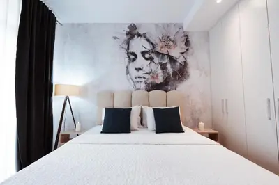 a bedroom with a large bed with a painting on the wall at inJoy in Belgrade