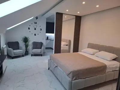 a bedroom with a bed and two chairs and a clock on the wall at Stef Lux Apartments in Belgrade
