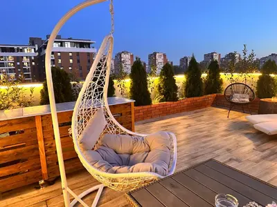 a hanging chair on a balcony with a view of a city at Golden Sunset Terrace Apartment Ana in Belgrade