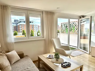 a living room with a couch and a table and windows at Golden Sunset Terrace Apartment Ana in Belgrade