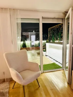 a white chair in a room with a sliding glass door at Golden Sunset Terrace Apartment Ana in Belgrade