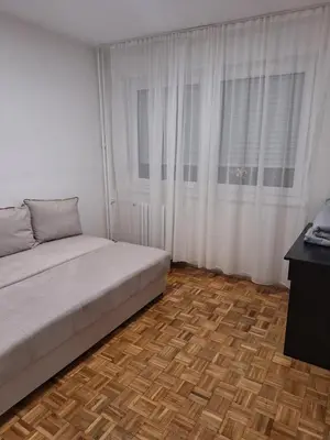 a bedroom with white curtains and a bed with a wooden floor at Toni apartment in Belgrade