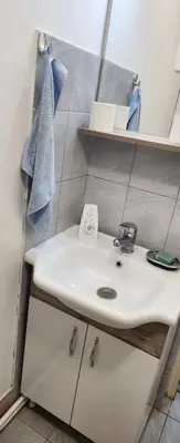 a bathroom with a white sink and shelves at Kristian 1 in Belgrade