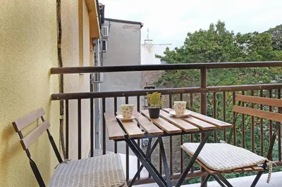 a wooden table and two chairs on a balcony at Apartment Paradise Slavija Tres in Belgrade