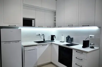 a white kitchen with white cabinets and a sink at Present Perfect Stay in Belgrade