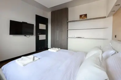 a bedroom with a white bed with a flat screen tv at Emma in Belgrade