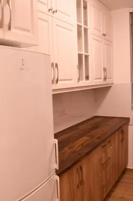 a kitchen with a white refrigerator and wooden cabinets at Loft 43 in Stara Pazova