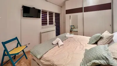 a bedroom with a bed and a chair and a television at Plavi zec apartman Zemun in Belgrade