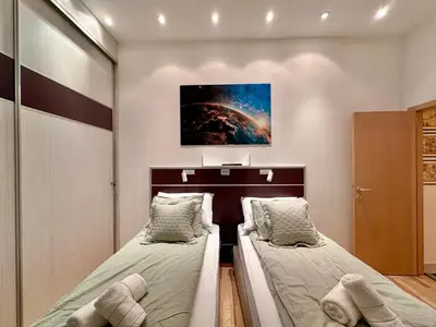 two beds in a small bedroom with a painting on the wall at Plavi zec apartman Zemun in Belgrade