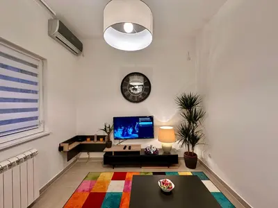 a living room with a tv and a colorful rug at Plavi zec apartman Zemun in Belgrade