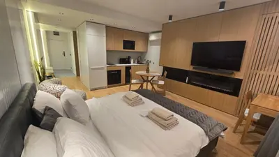 a living room with a white bed and a flat screen tv at Genex SPA in Belgrade