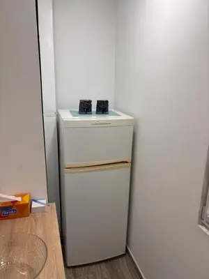 a white refrigerator in a kitchen next to a wall at Aktiva Apartments in Belgrade